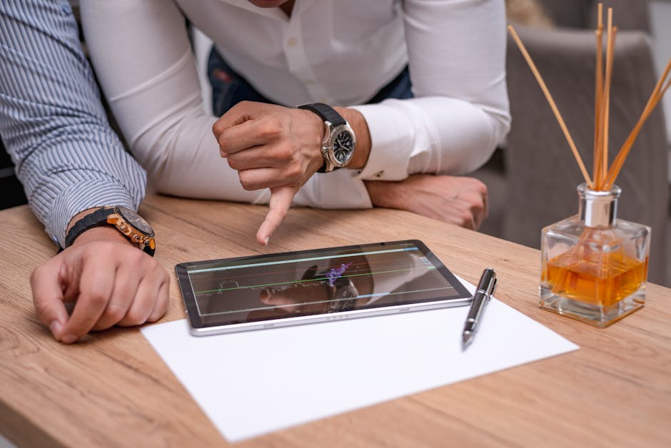Two business professionals discussing a graph on a digital tablet over a wooden table.